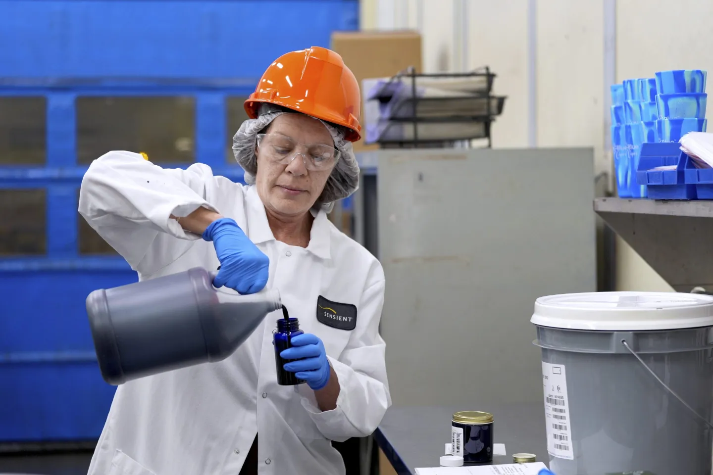 A scientist pours liquid out of a big bottle into a small container