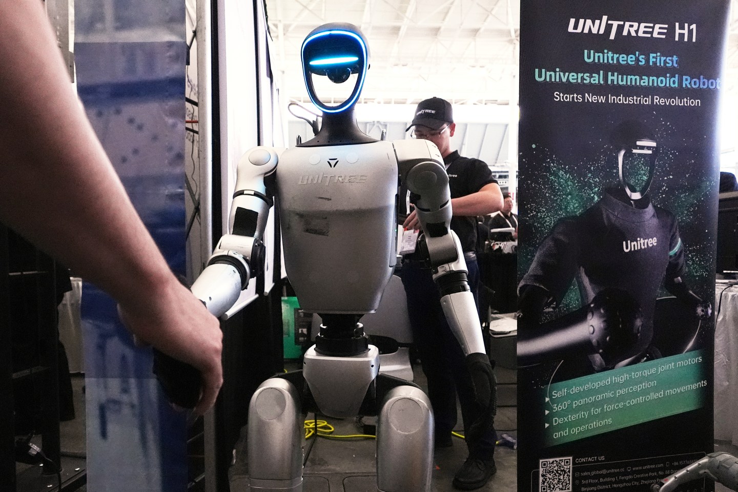A Unitree robot shakes hands with a convention guest at the Robotics Summit & Expo, Wednesday, April 30, 2025, in Boston. (AP Photo/Charles Krupa)