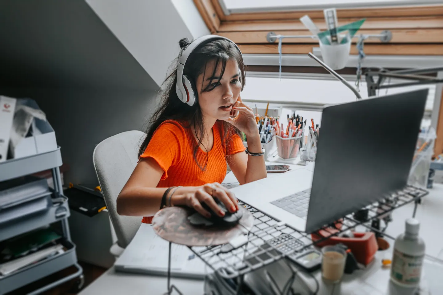 Woman with earphones using a computer at a desk