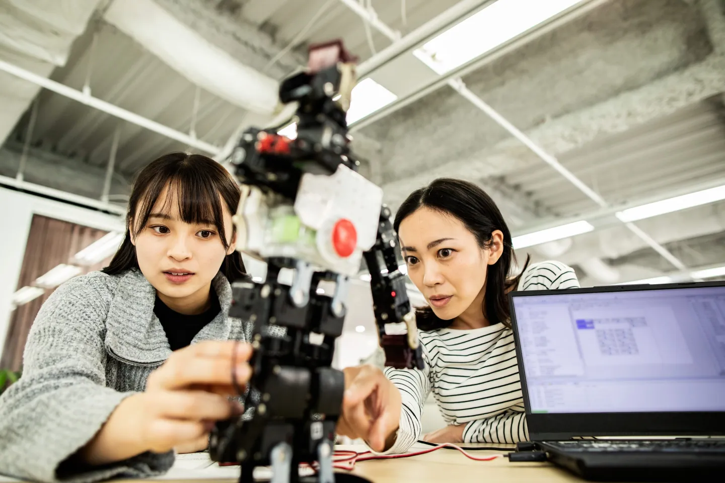 A female researcher at a start-up company examining a robot prototype