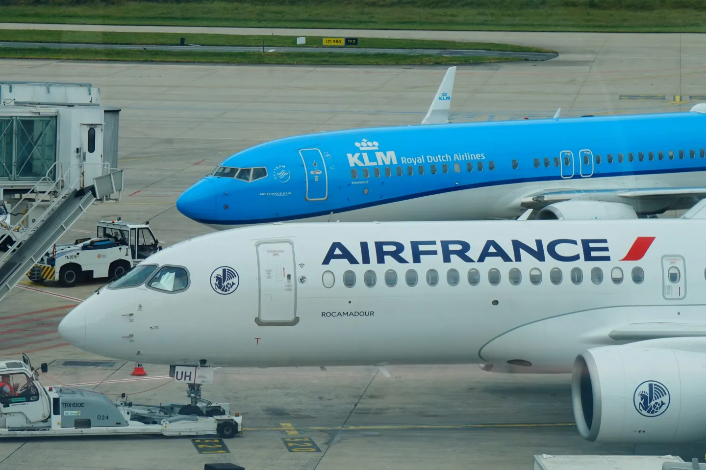 A view on two airplanes of the AirFrance KLM Group, parked at the gate of Paris Charles de Gaulle international Airport. Roissy en France, Paris, Ile de France, France. KLM and Air France.