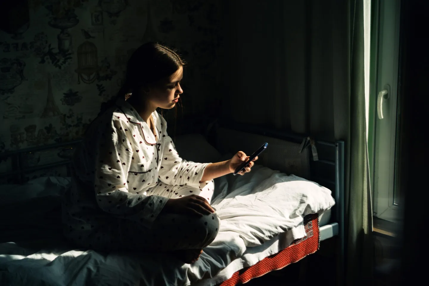 Teen girl using smartphone on her bed in the dark