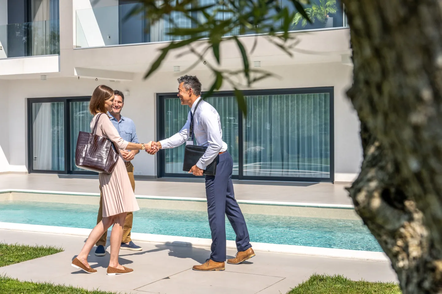 People shaking hands outside a pool in a backyard.