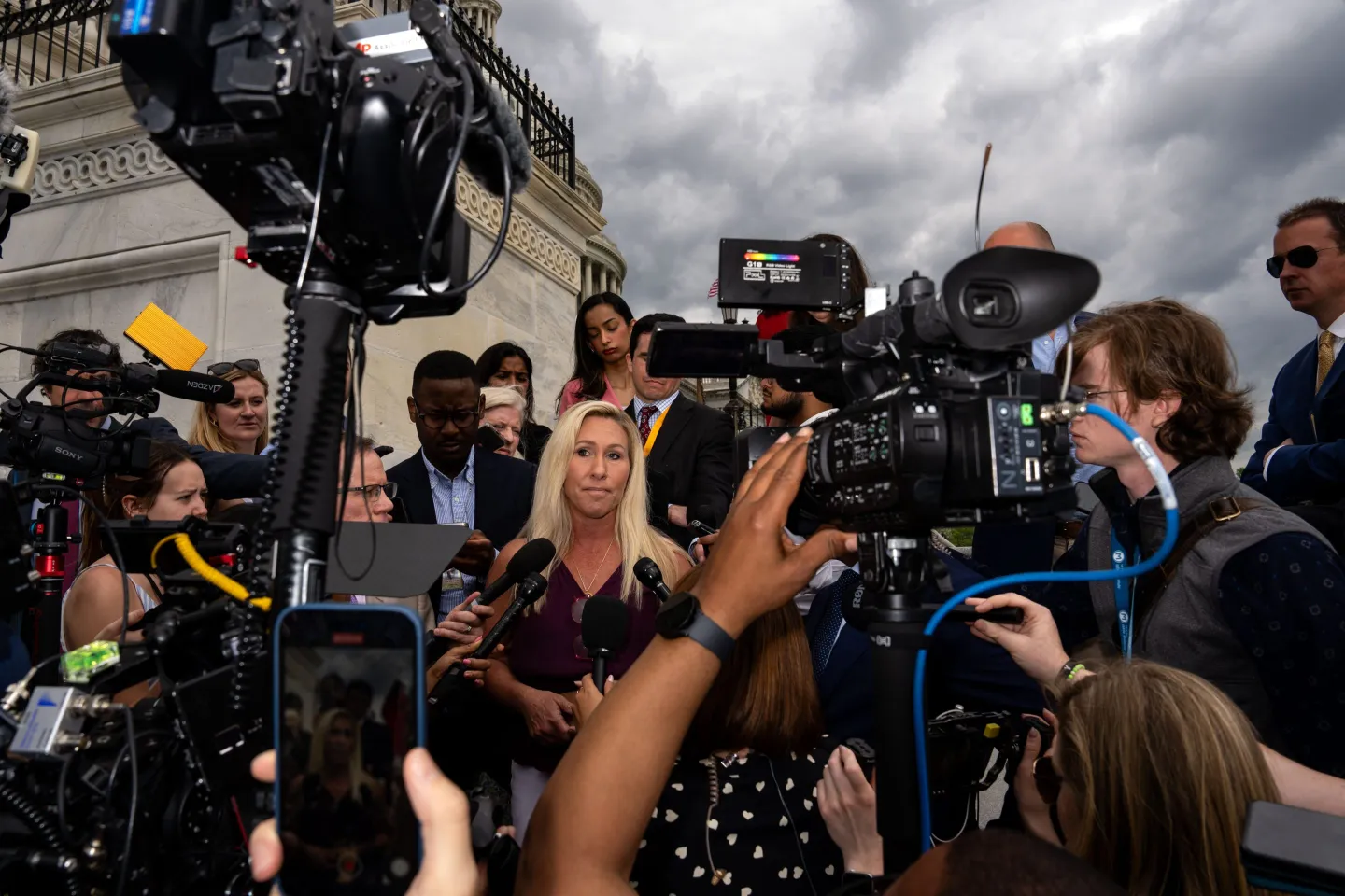 Television cameras and news reporters press around U.S. Representative Majorie Taylor Green as she answers questions outside the U.S. Capitol building.