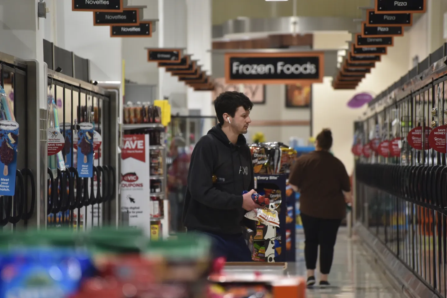 A man goes grocery shipping in the frozen foods aisle.