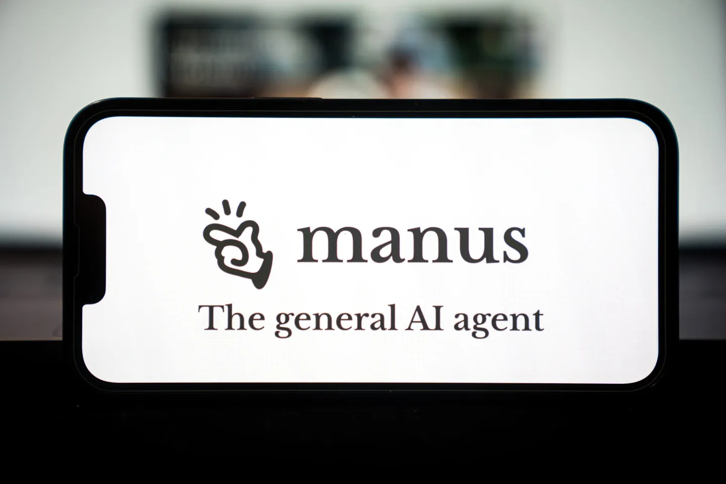 A phone displaying a title saying "manus" and "the general AI agent."