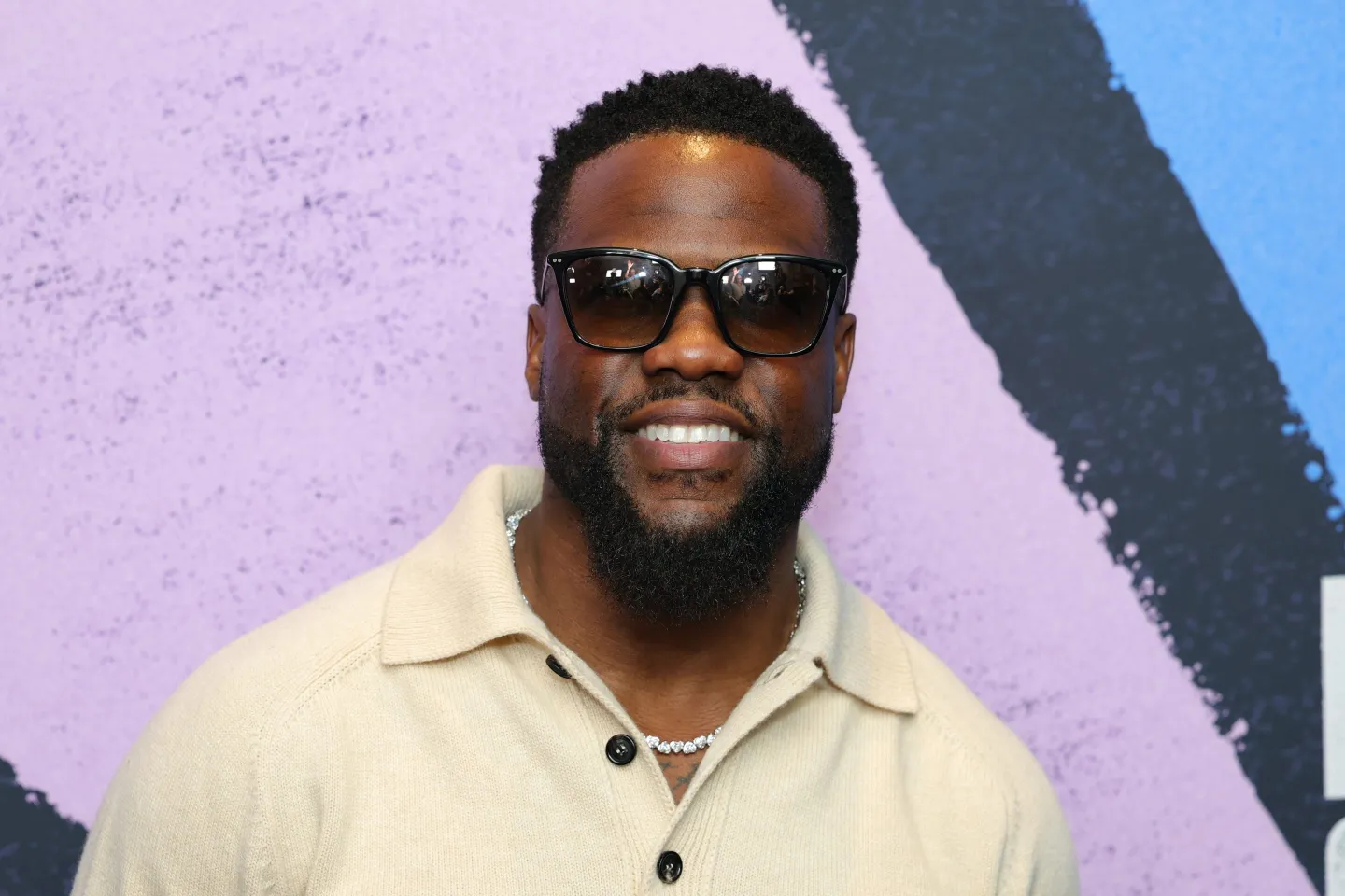 Kevin Hart smiles for the camera wearing sunglasses