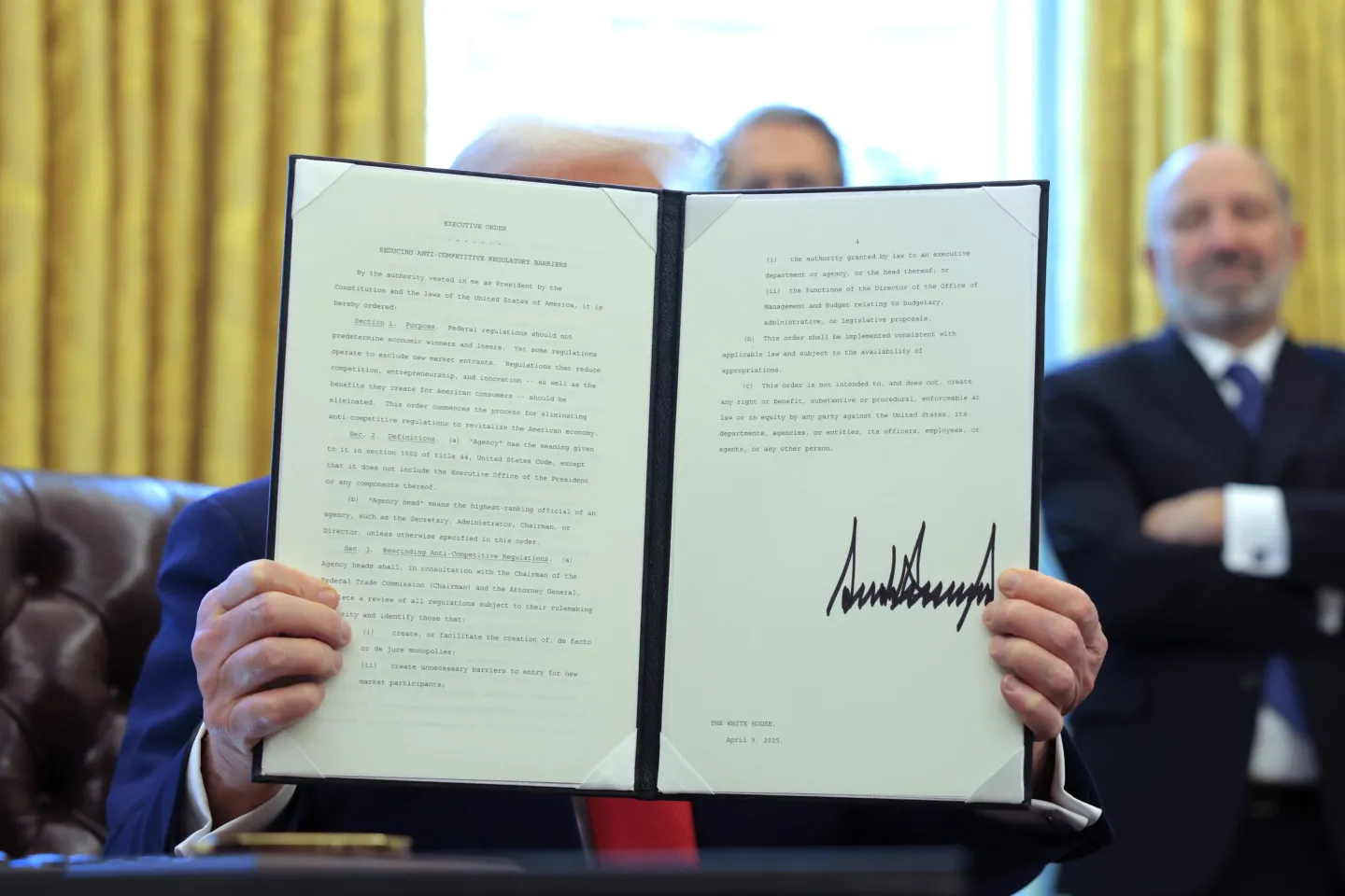 President Donald Trump displays a signed executive order in the Oval Office