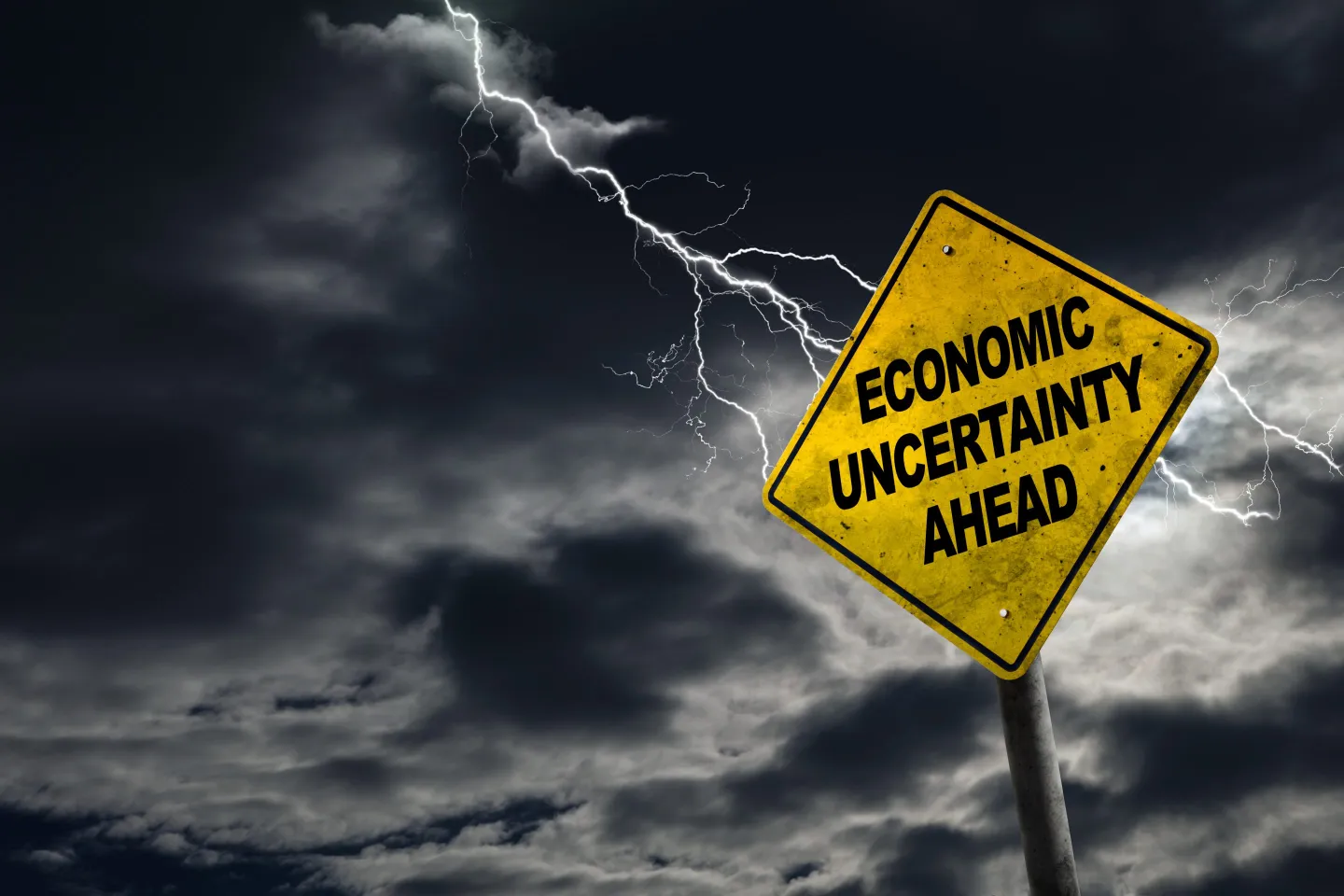 A sign says economic uncertainty ahead on a cloudy dark sky